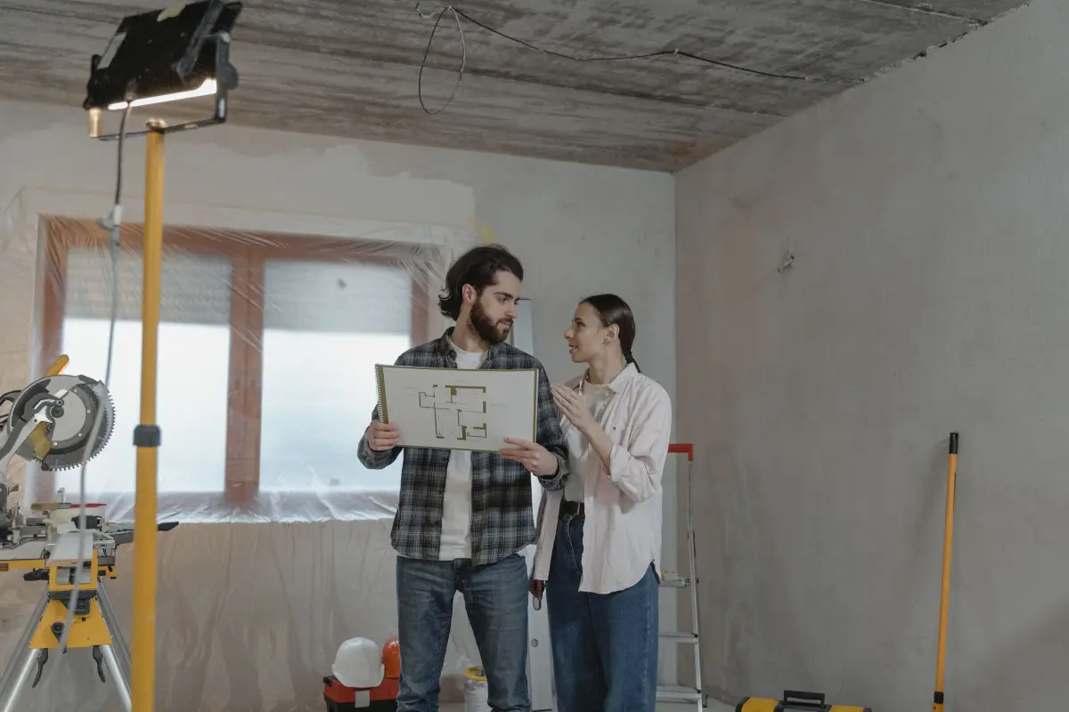 Couple consultant un plan dans une pièce en rénovation